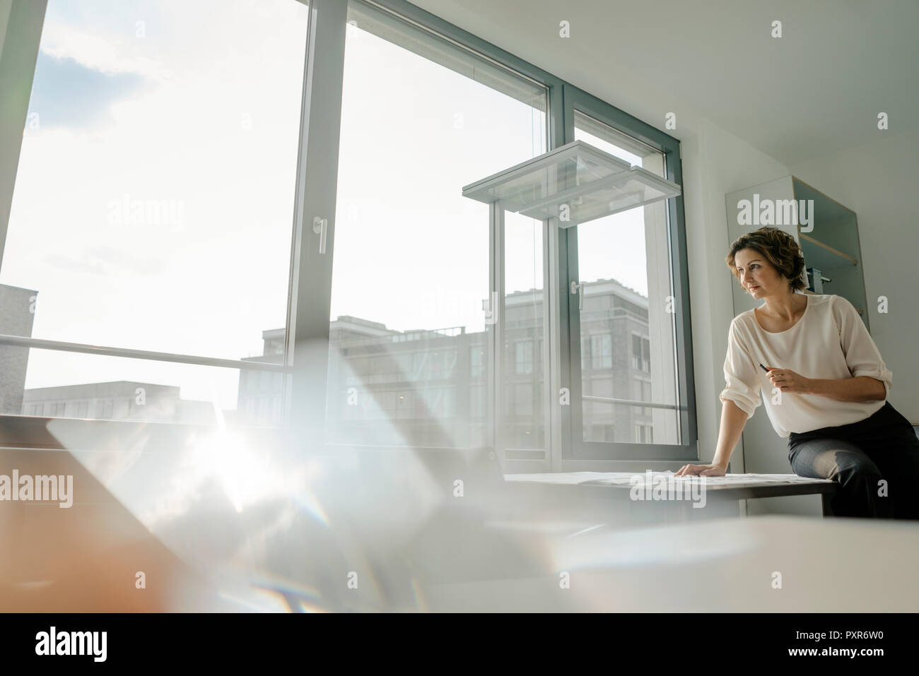 Imprenditrice lavoro in ufficio, seduto sulla scrivania Foto Stock