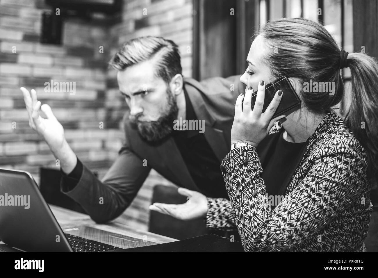 Sottolineato arrabbiato business uomo e donna con notebook guardando seduta a tavola urlando al computer. Le emozioni negative nella vita in ufficio. Problemi a Foto Stock