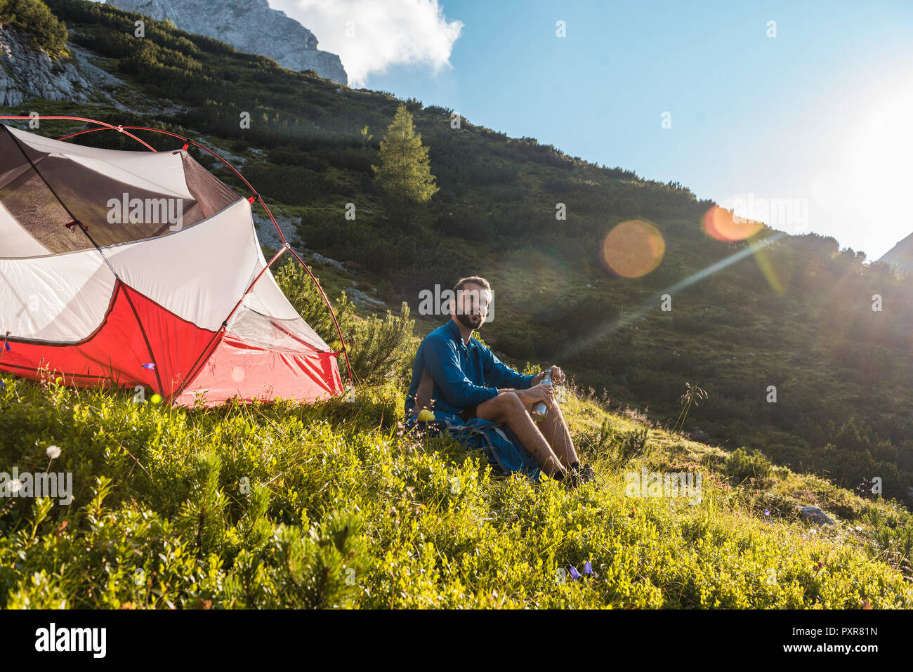 Austria, Tirolo, Escursionista prendendo una pausa, seduta in erba per la sua tenda Foto Stock