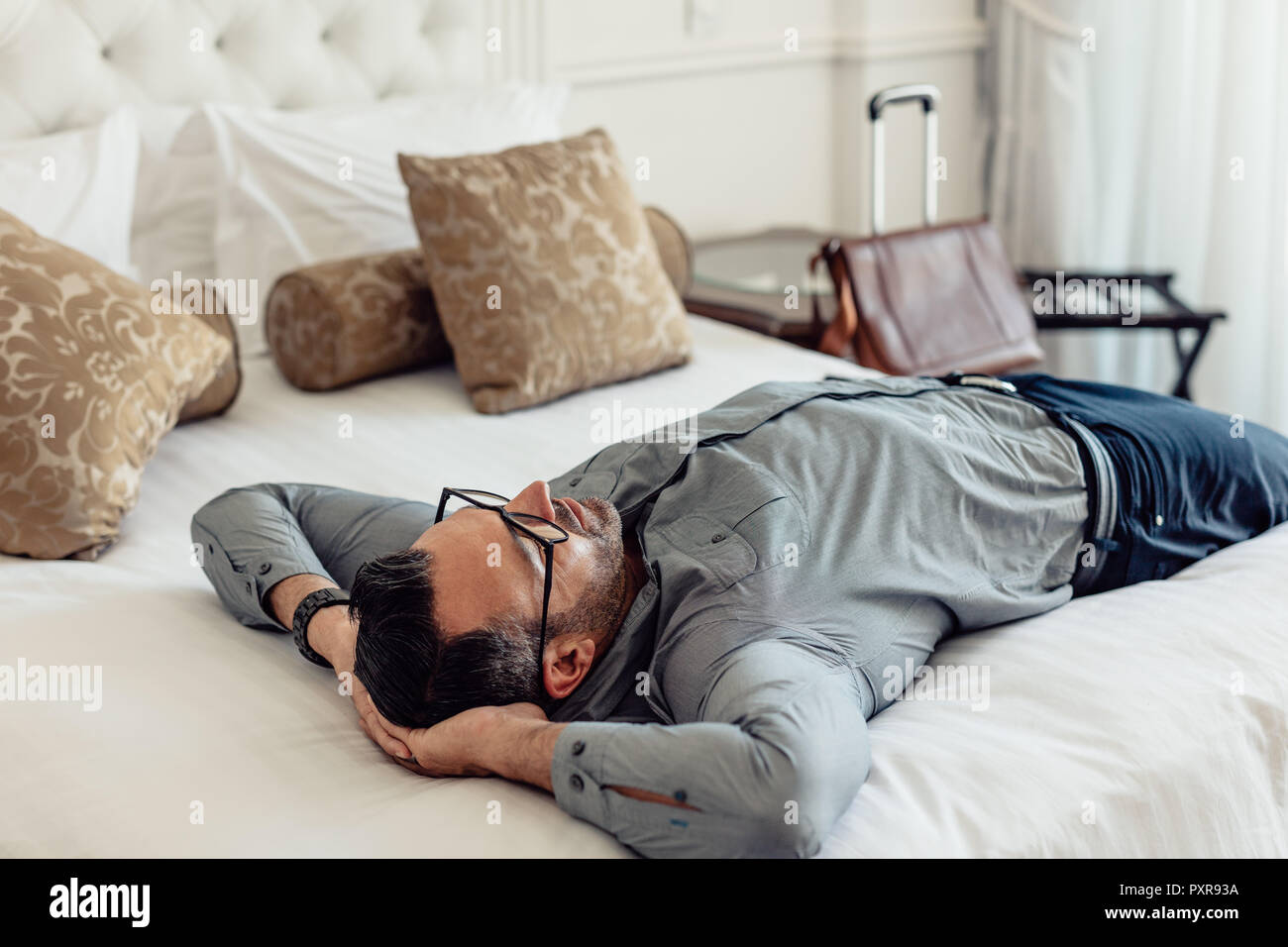 Ritratto di stanchi imprenditore caucasico dormire su un letto in una camera d'albergo. Imprenditore maturo rilassante sul letto dopo il viaggio. Foto Stock