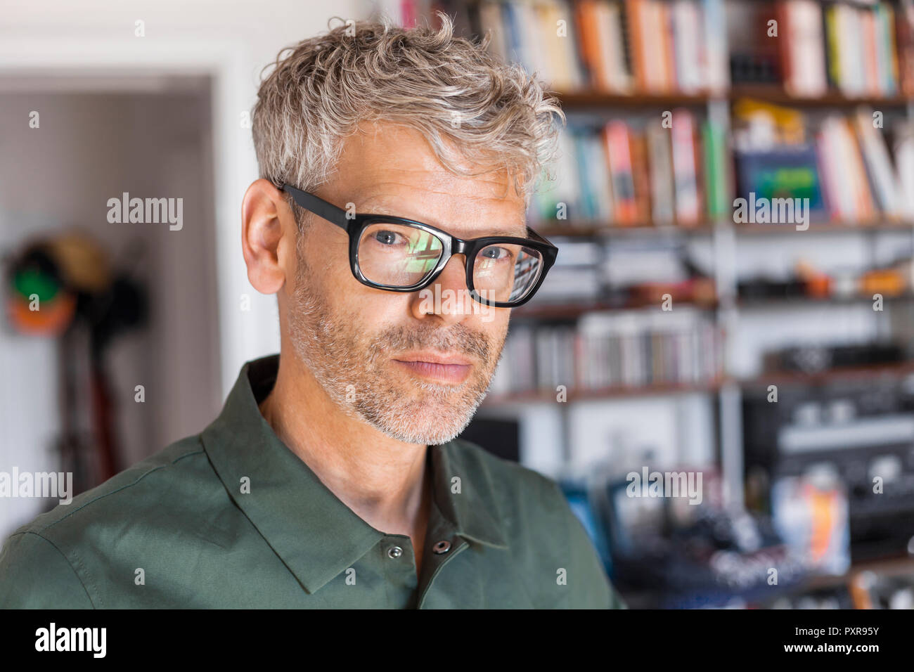 Ritratto di uomo maturo con i capelli grigi e di stoppie con gli occhiali a casa Foto Stock