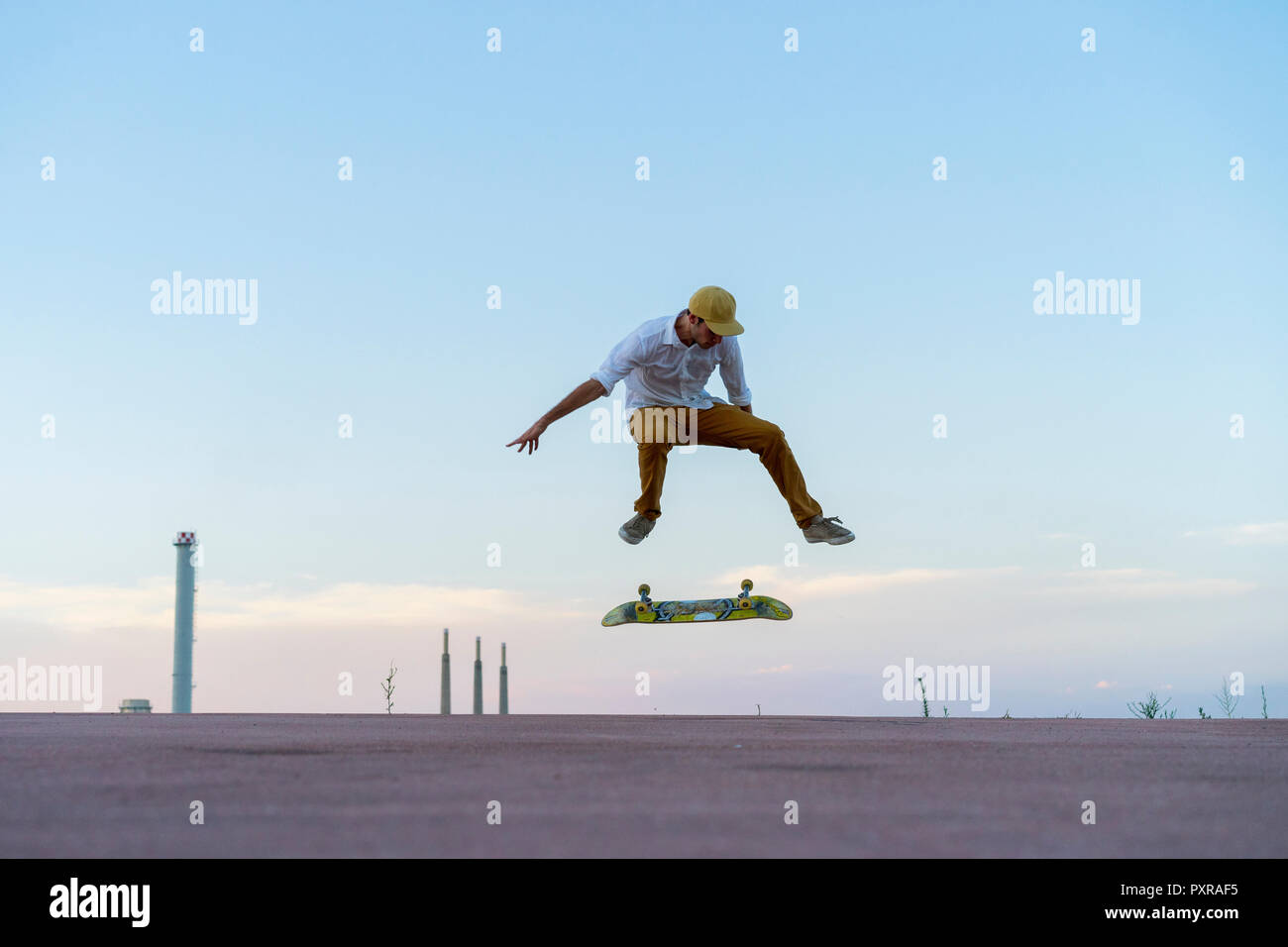 Giovane uomo facendo uno skateboard trick su una corsia al crepuscolo Foto Stock