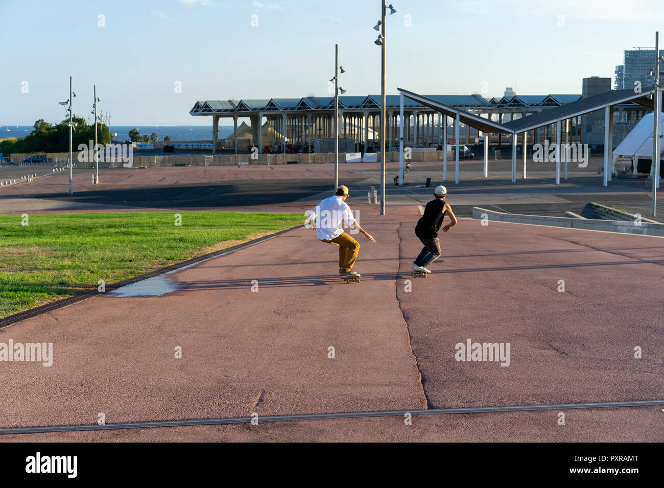 Due giovani uomini a cavalcare giù lungo una corsia con skateboard Foto Stock