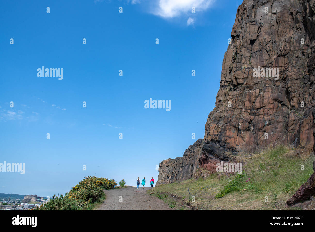 Molte persone a piedi lungo il Salisbury Crags (Holyrood Park) in Scozia Foto Stock