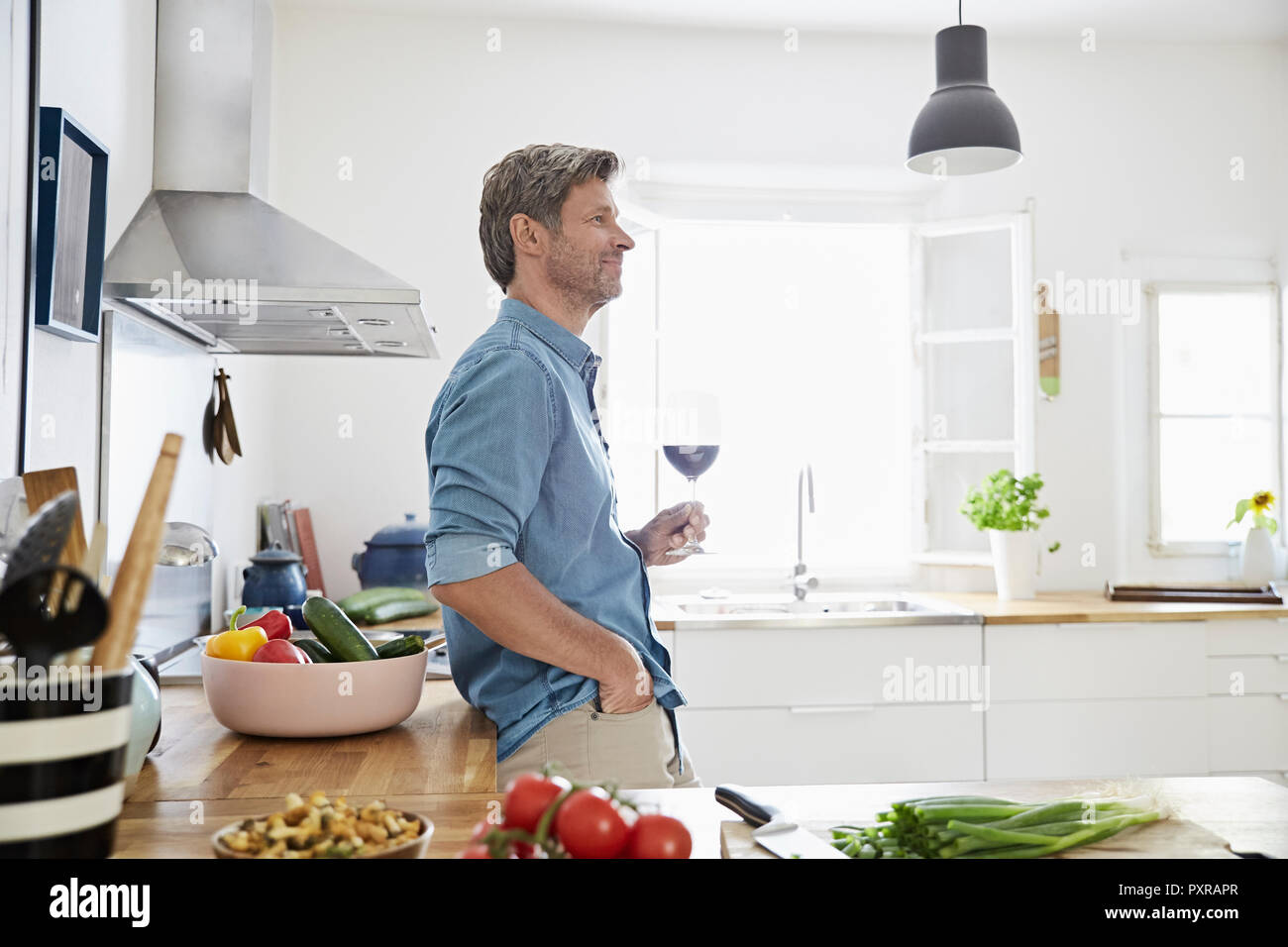 Uomo maturo nella sua cucina degustazione di vino rosso Foto Stock