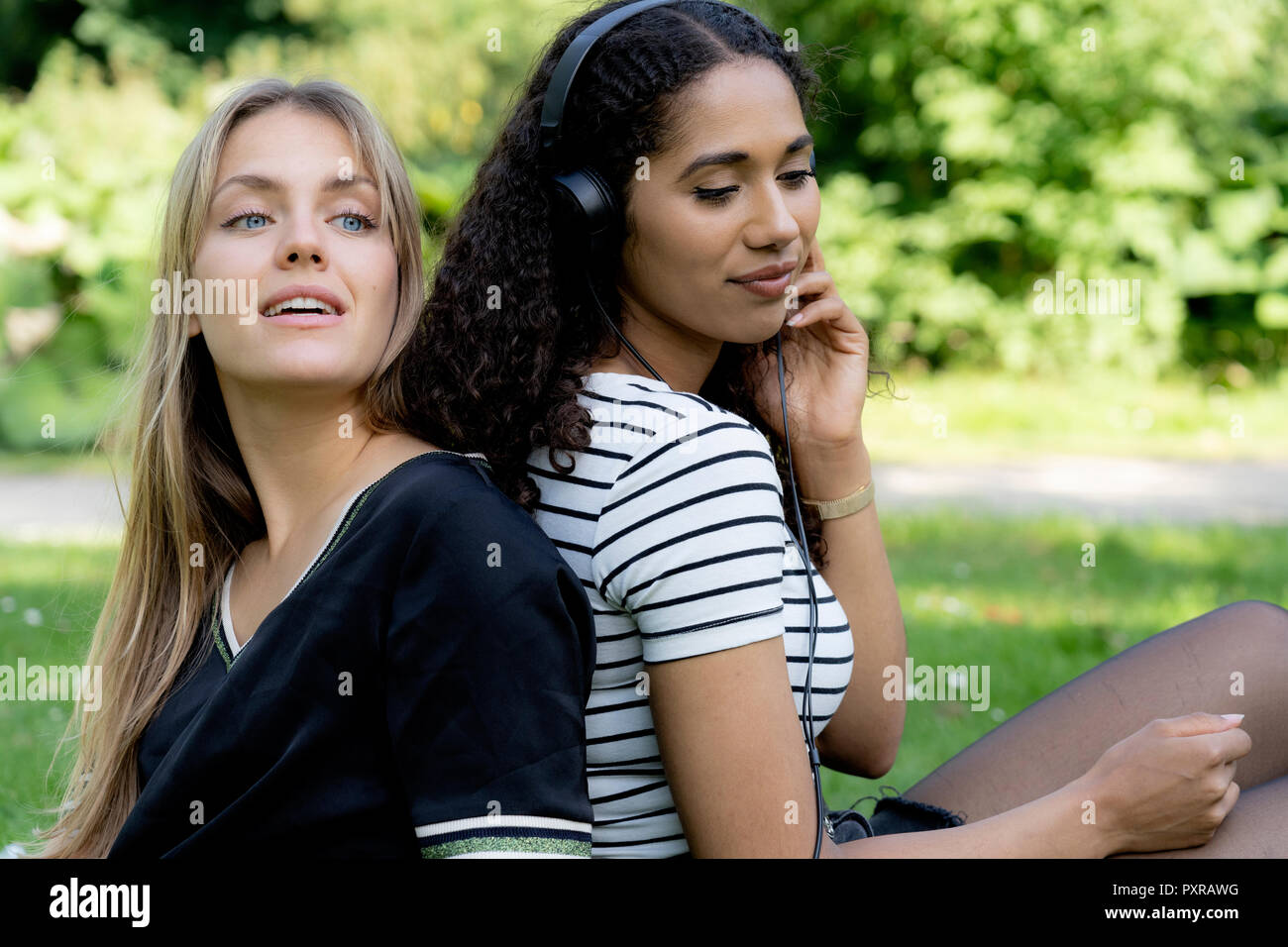 Due amiche in un parco e ascolto di musica Foto Stock