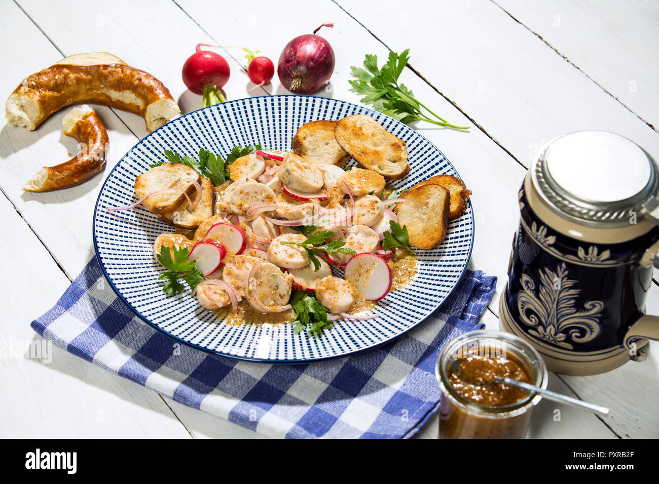 Bavarese di salsiccia di vitello con insalata di arrosto di pretzel rotoli, senape dolce, salatini, radicchio rosso e il boccale di birra Foto Stock