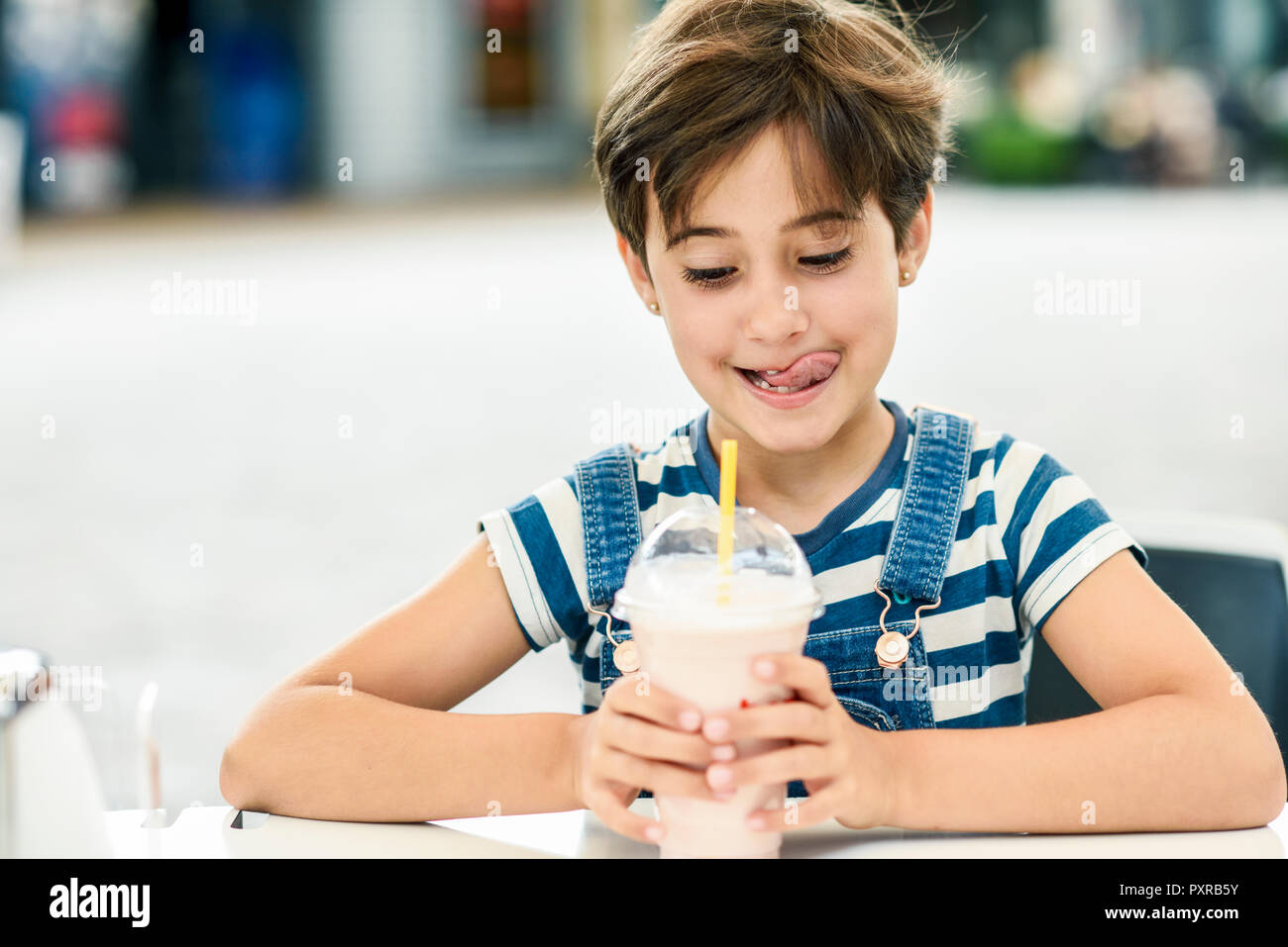 Ritratto di bambina con gustoso frullato fragole a pavement cafe Foto Stock