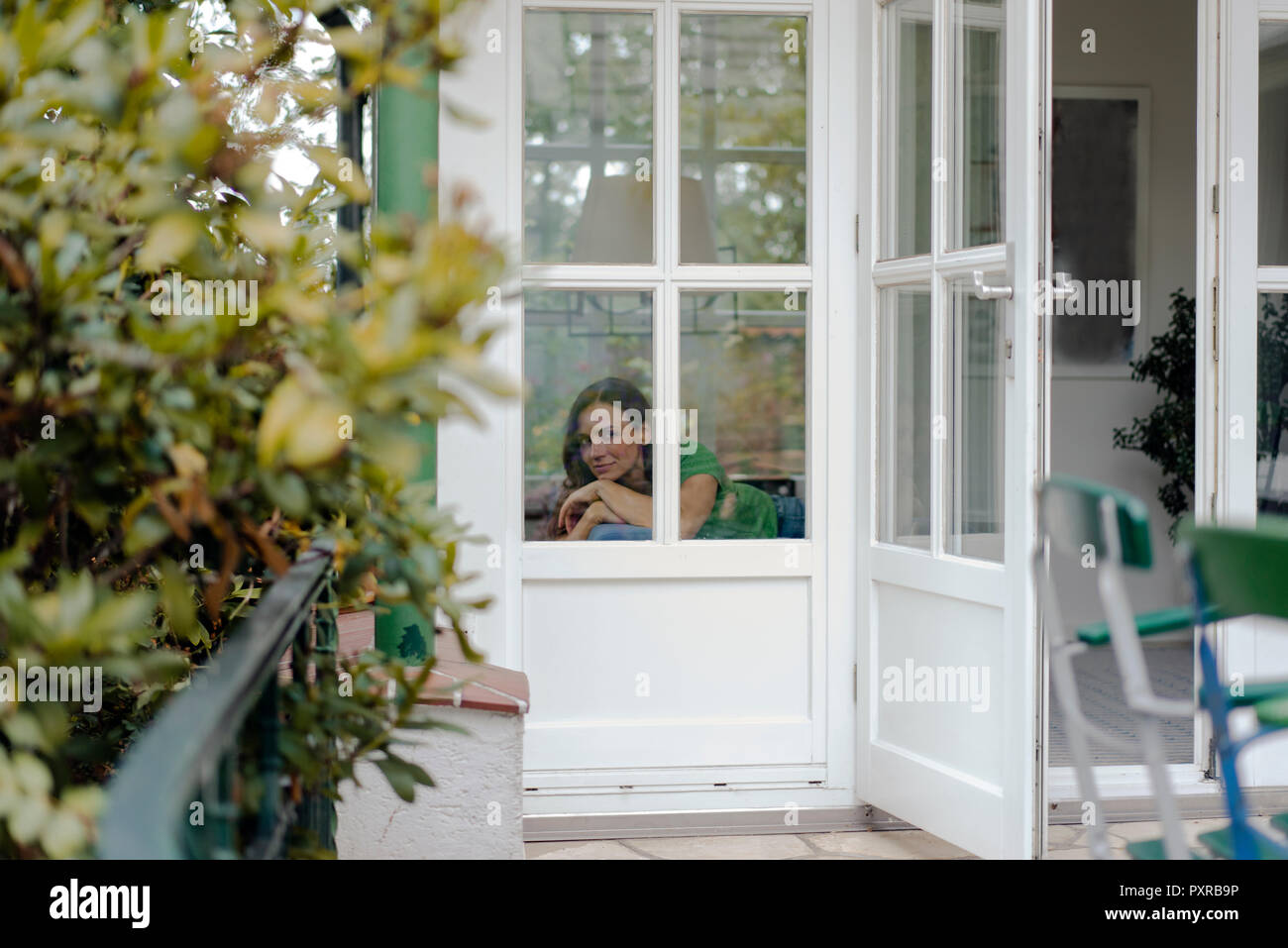 Donna matura in appoggio sul lettino a casa guardando lateralmente Foto Stock