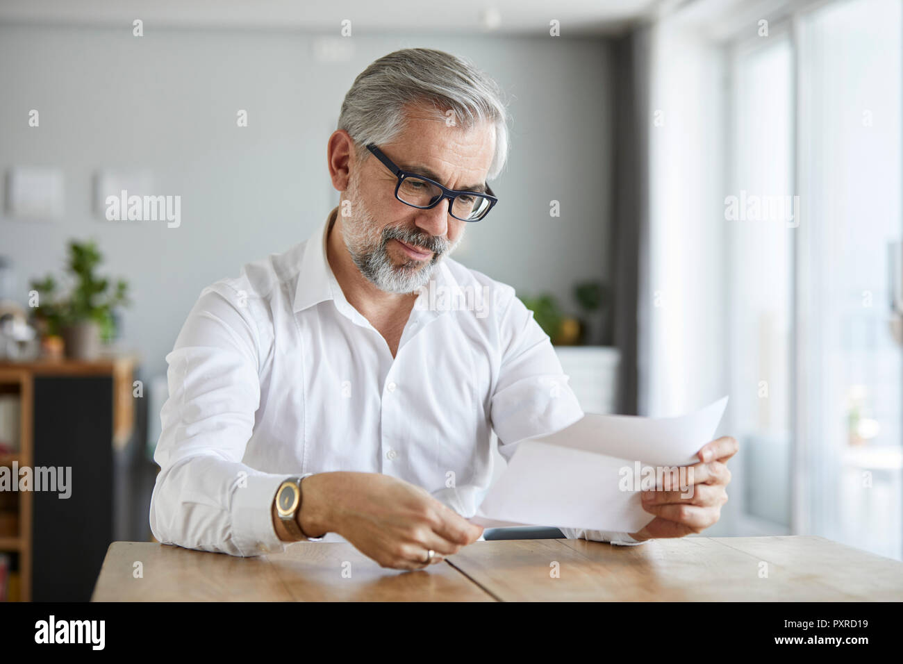 Ritratto di uomo maturo lettura la lettera a casa Foto Stock
