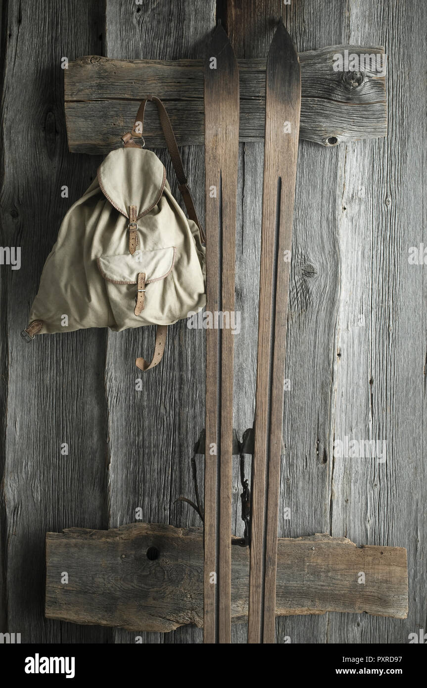 Sci di legno vecchio e uno zaino su una rustica parete in legno Foto Stock