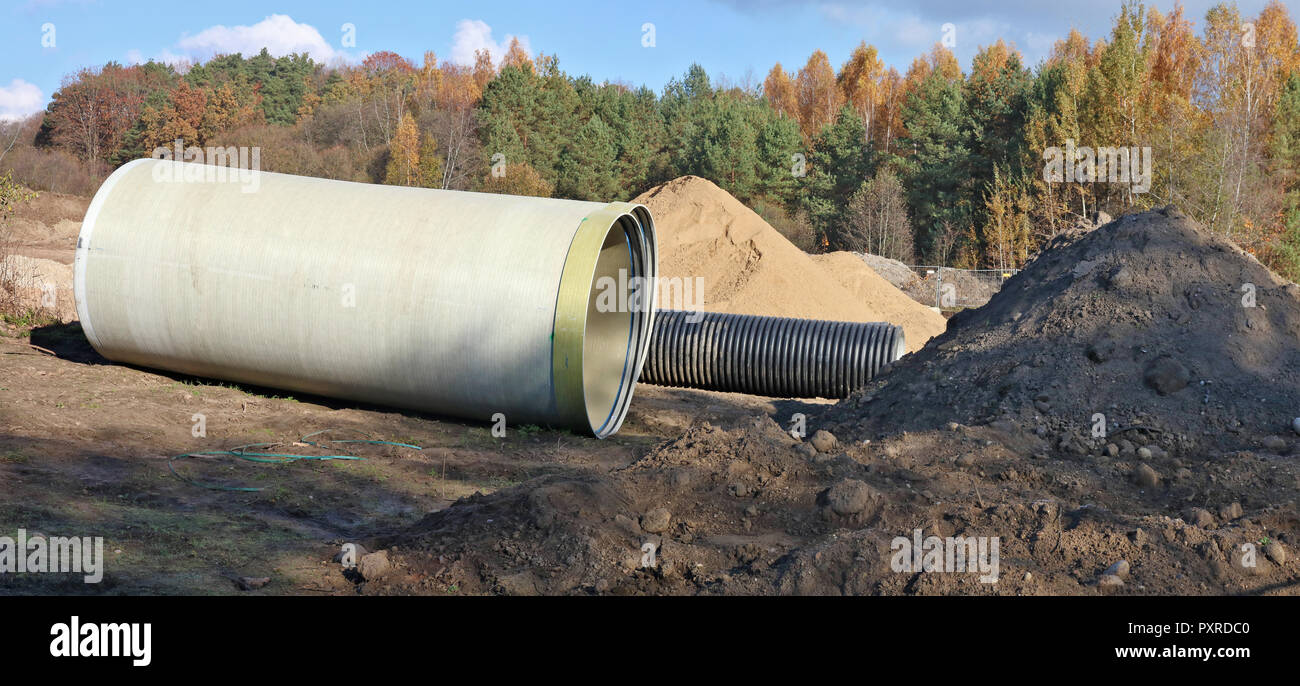 Grandi tubi fognari e la pila di sabbia in una foresta di autunno sito in costruzione. Collage panoramico da diversi outdoor soleggiata giornata di ottobre scatti Foto Stock