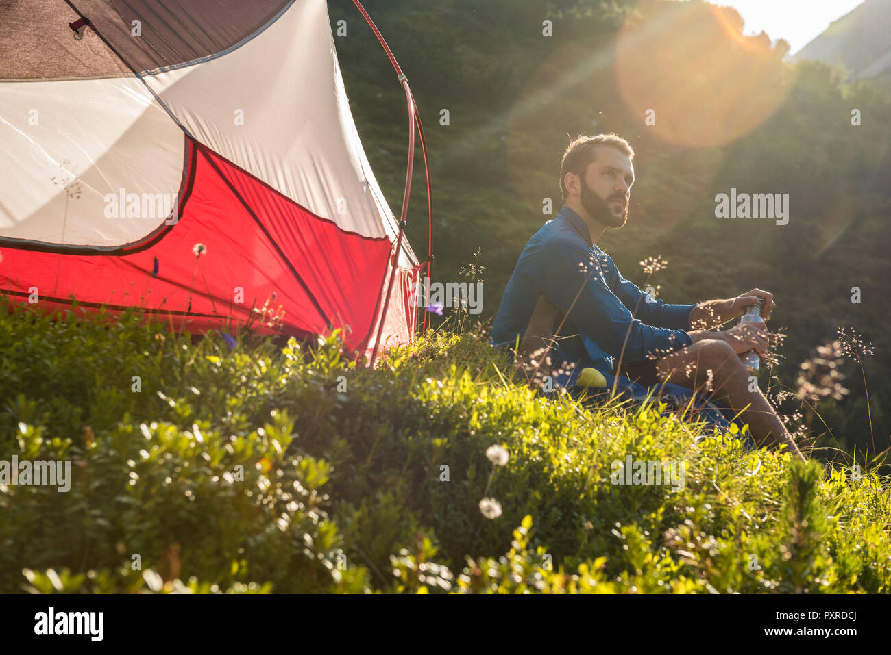 Austria, Tirolo, Escursionista prendendo una pausa, seduta in erba per la sua tenda Foto Stock