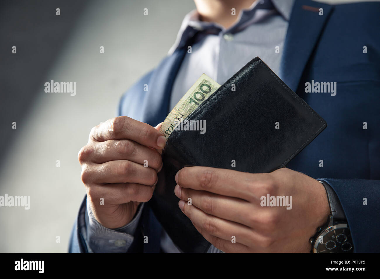 Uomo elegante in tuta tira fuori il suo denaro dal portafoglio. Concezione della gestione del denaro. Foto Stock