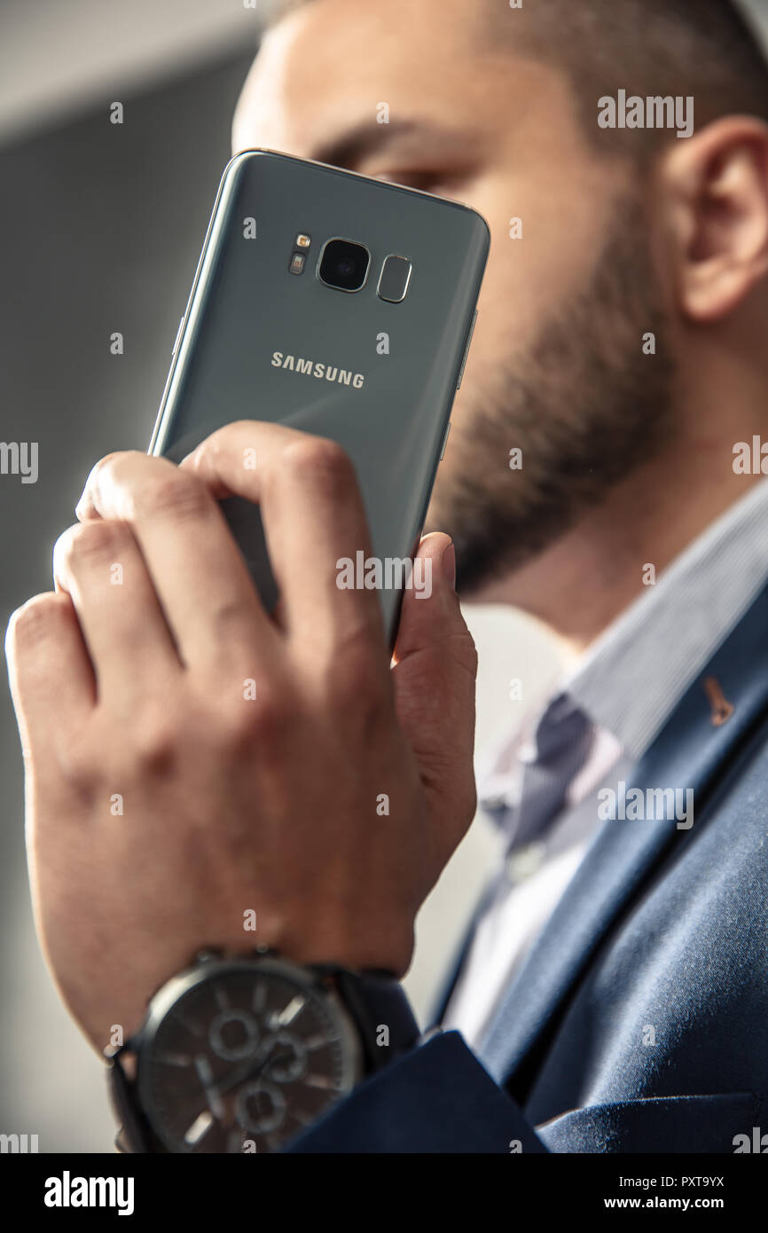 WROCLAW, Polonia - Ottobre 17th, 2018: un uomo elegante in tuta trattiene il suo smartphone. Samsung Galaxy S8 è Android smartphone phablet prodotta da Samsun Foto Stock