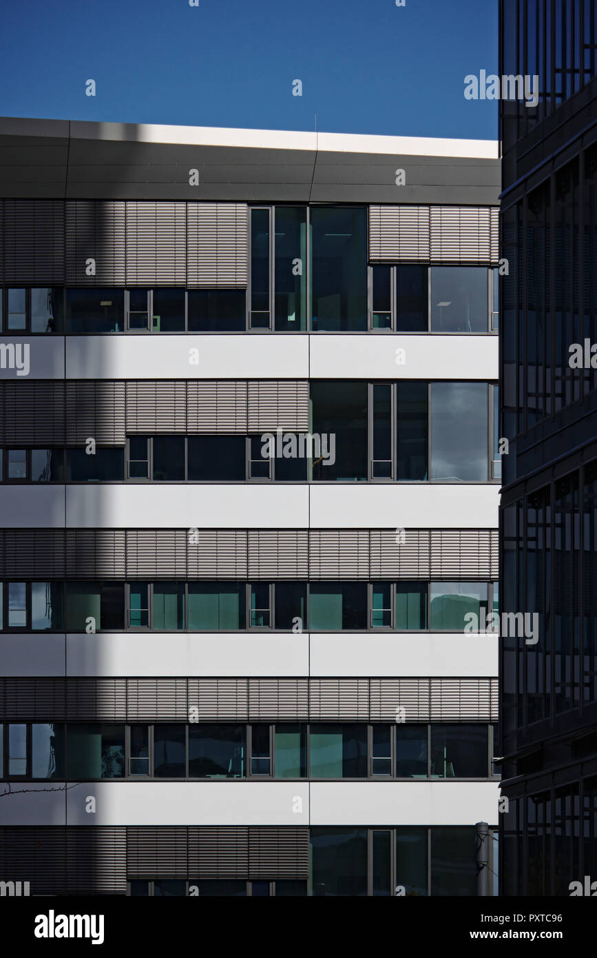 Facciata di alto edificio di uffici parzialmente illuminata dalla luce del sole con il secondo edificio in ombra in primo piano Foto Stock