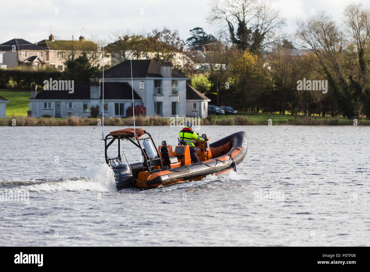 Capitaneria di porto la barca di salvataggio sulla velocità di Lough Neagh con case in background vicino Kinnego Marina, Isola di Oxford, N.Irlanda. Foto Stock