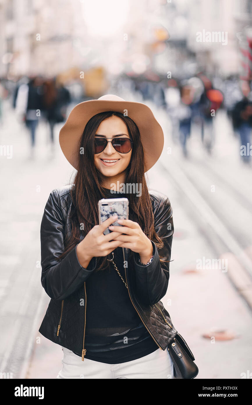 Elegante ragazza in marrone cappello usando il telefono in Istanbul TURCHIA Foto Stock
