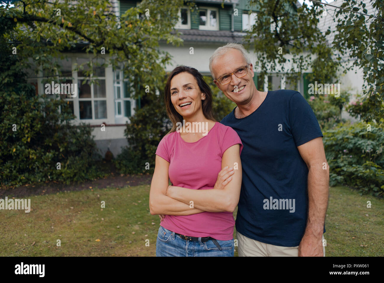 Felice Coppia matura in piedi nel giardino della loro casa Foto Stock