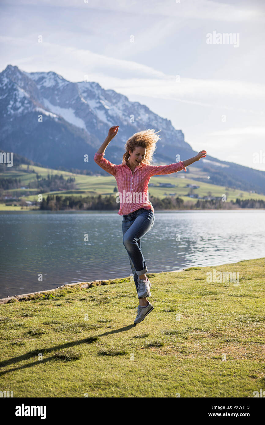 Austria, Tirolo, Walchsee, donna felice saltando al lago Foto Stock