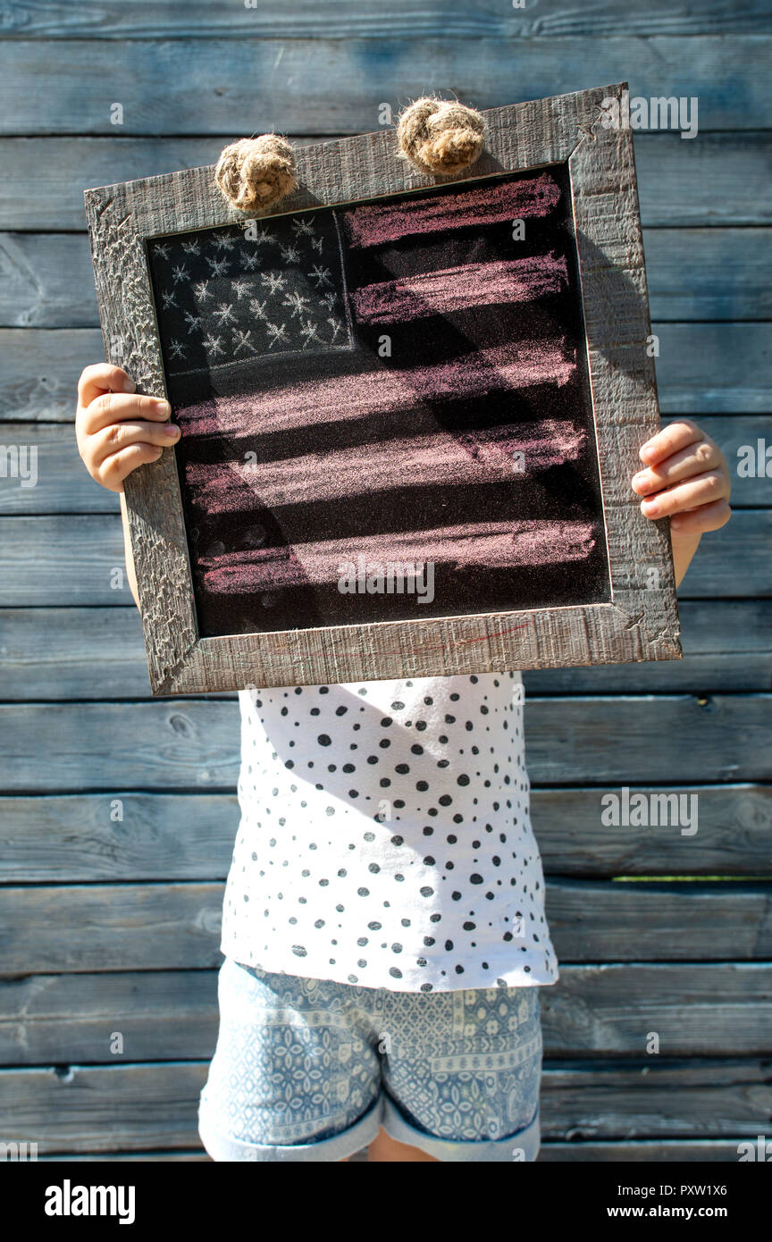 Bambina tenendo il telaio in legno con noi-bandiera americana Foto Stock