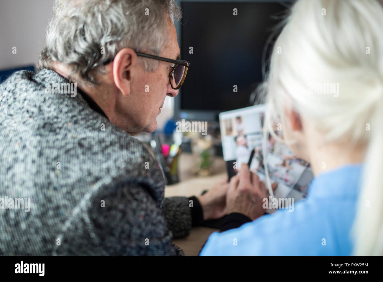 Due colleghi più anziani lavorando insieme alla scrivania in ufficio esaminando le foto Foto Stock