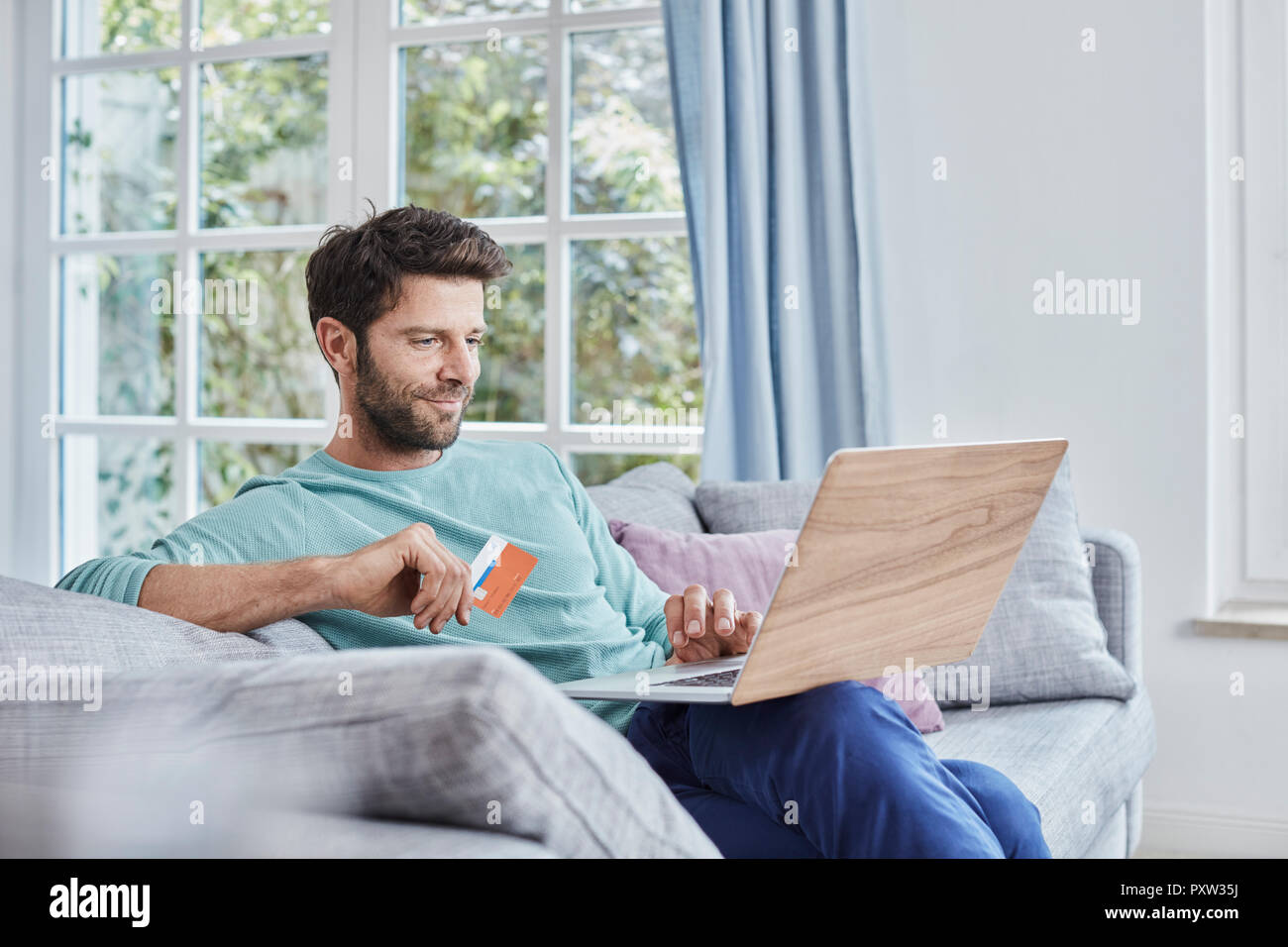 Uomo sorridente a casa lo shopping online Foto Stock
