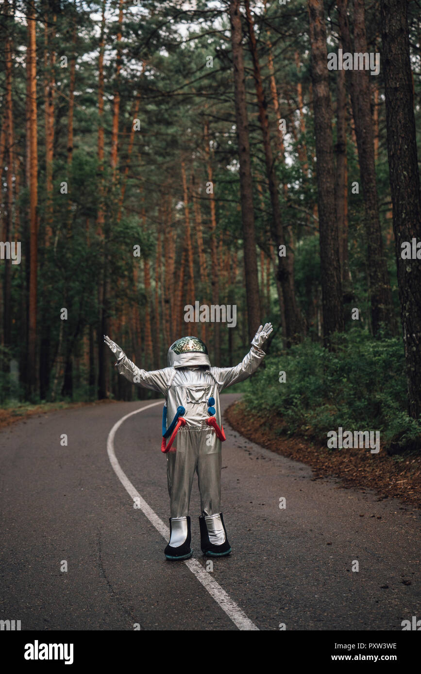 Spaceman esplorando la natura, hichhiking su strada in foreat Foto Stock