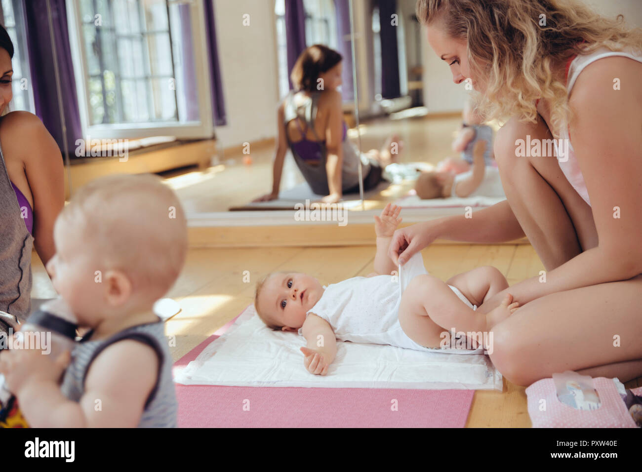 Madre cambiare i pannolini del bambino nella camera di esercizio Foto Stock