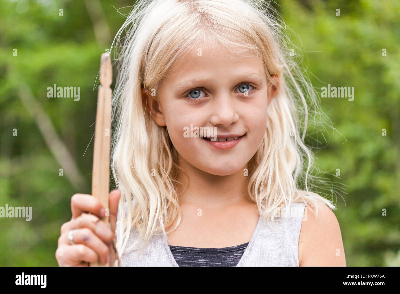 Ritratto di sorridente ragazza con bastone di legno all'aperto Foto Stock