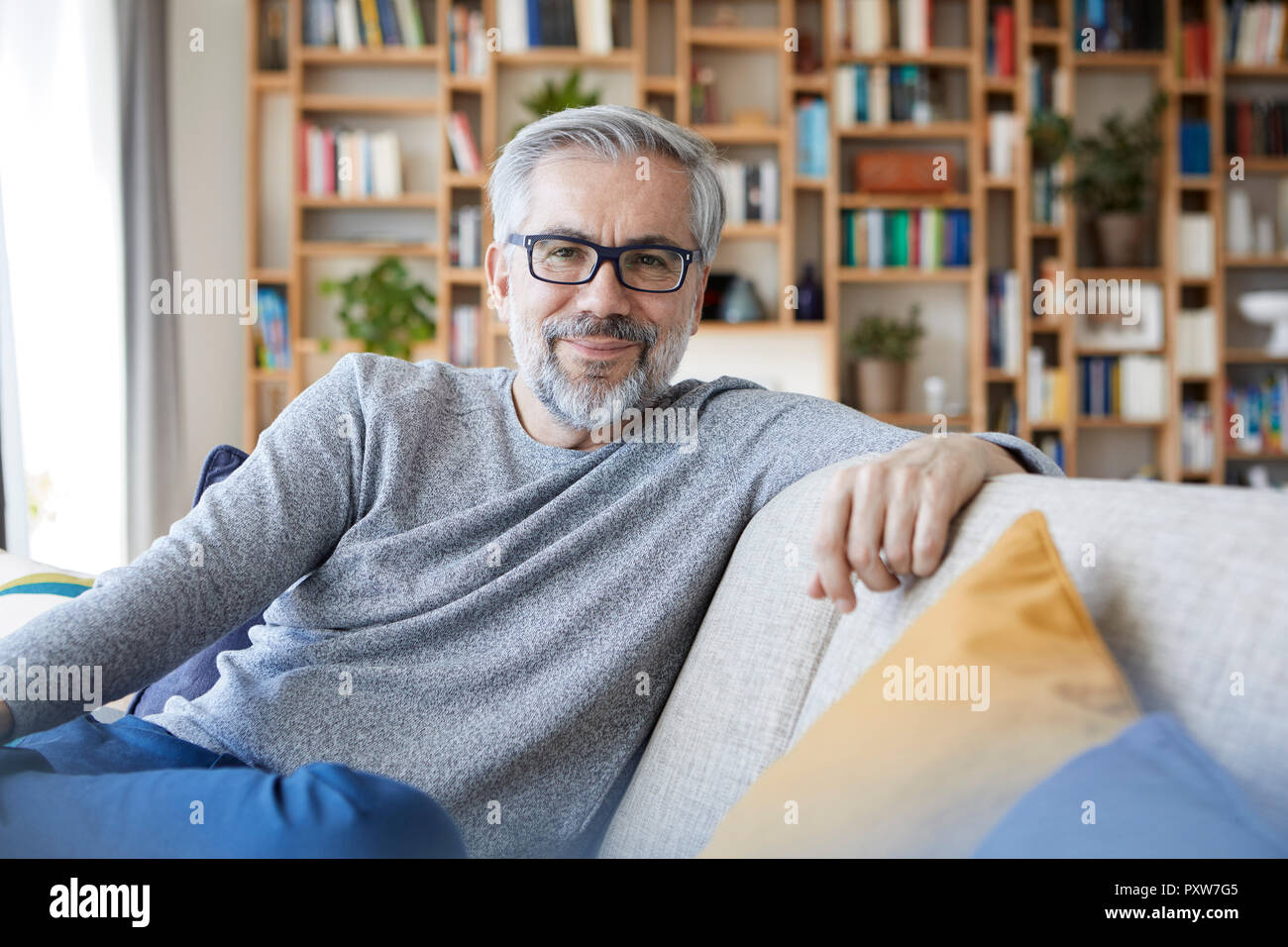 Ritratto di sorridere uomo maturo rilassante sul lettino a casa Foto Stock