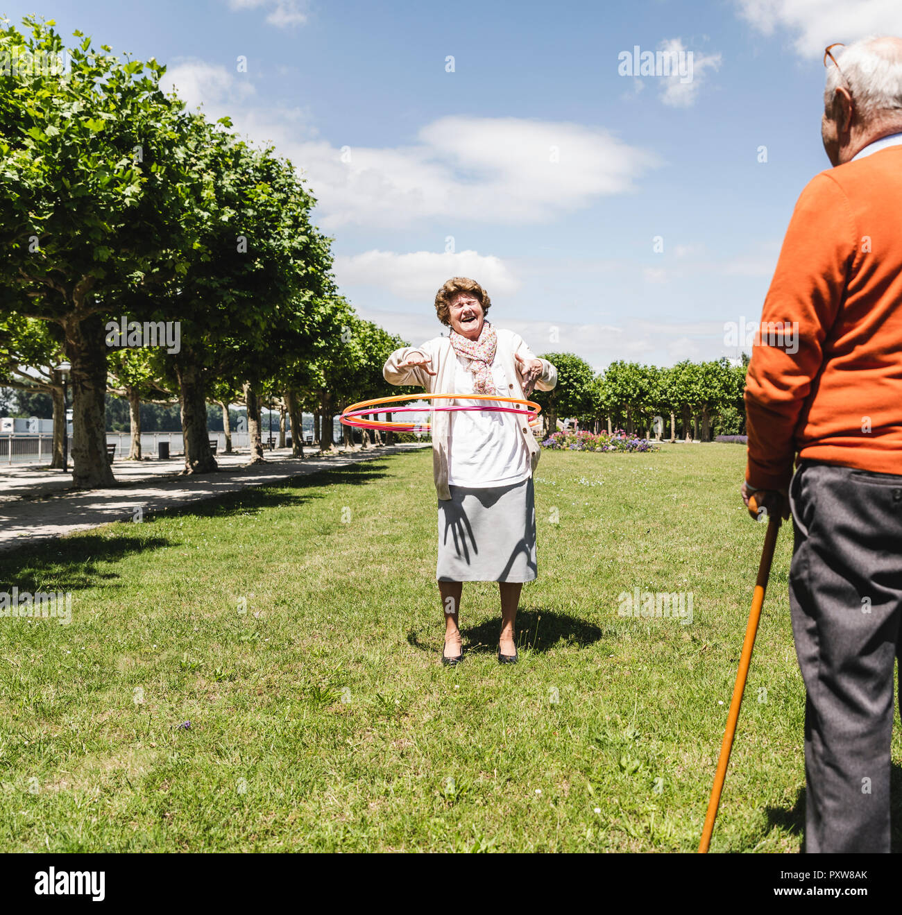 Senior guardando la signora anziana giocando con un hoola hoop Foto Stock