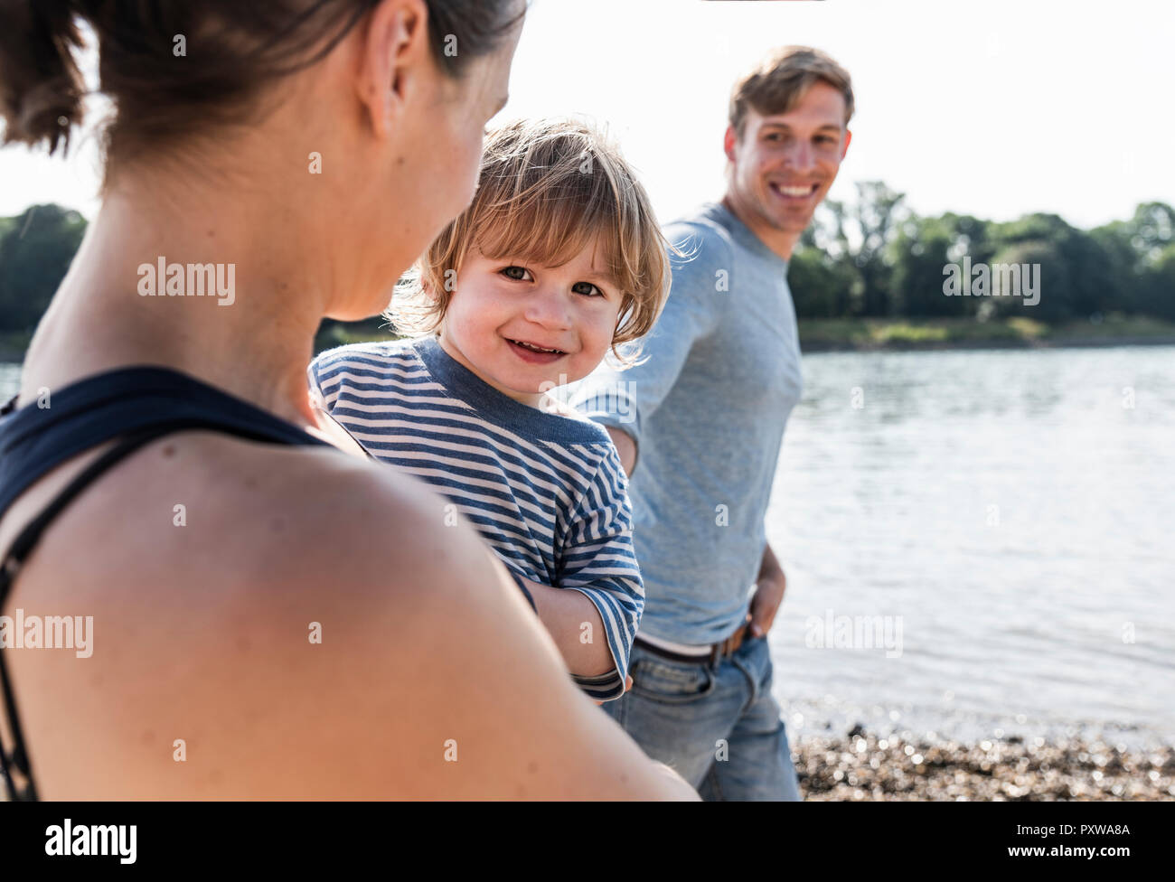 La famiglia felice passeggiare lungo il fiume su un bel giorno di estate Foto Stock