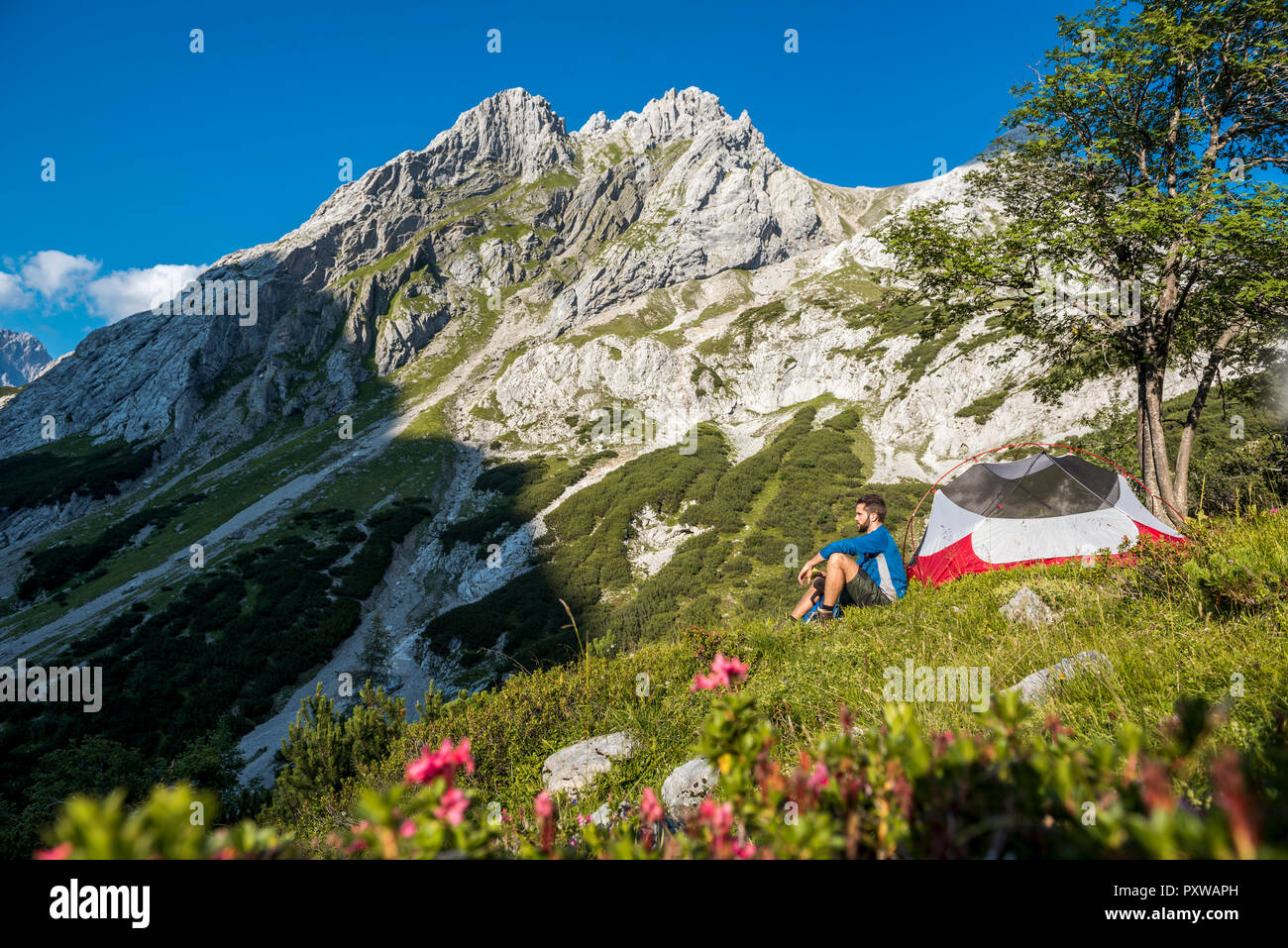Austria, Tirolo, Escursionista prendendo una pausa, seduta in erba per la sua tenda Foto Stock