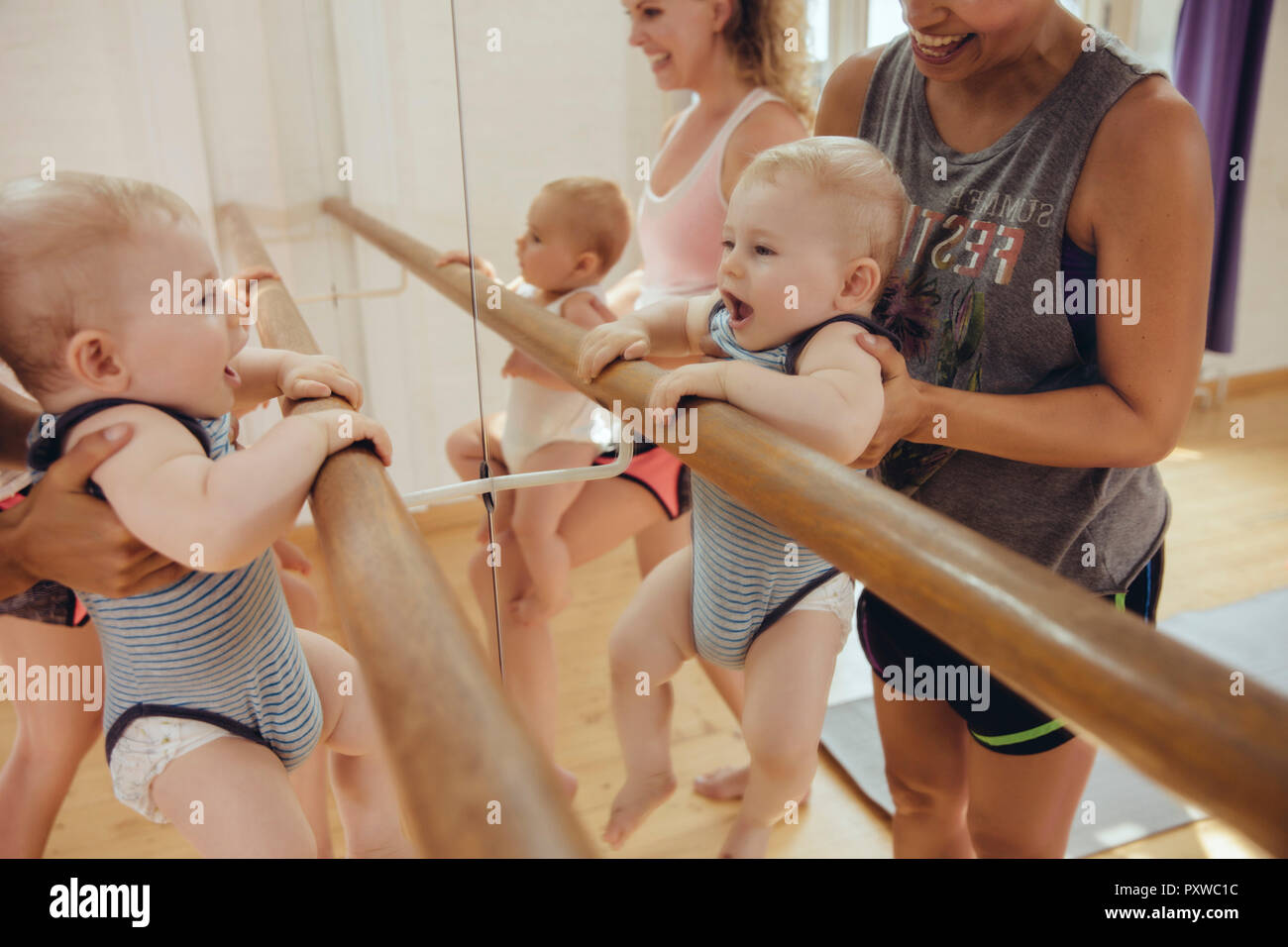 Due mamme con i loro bambini piccoli a barre in studio di danza Foto Stock