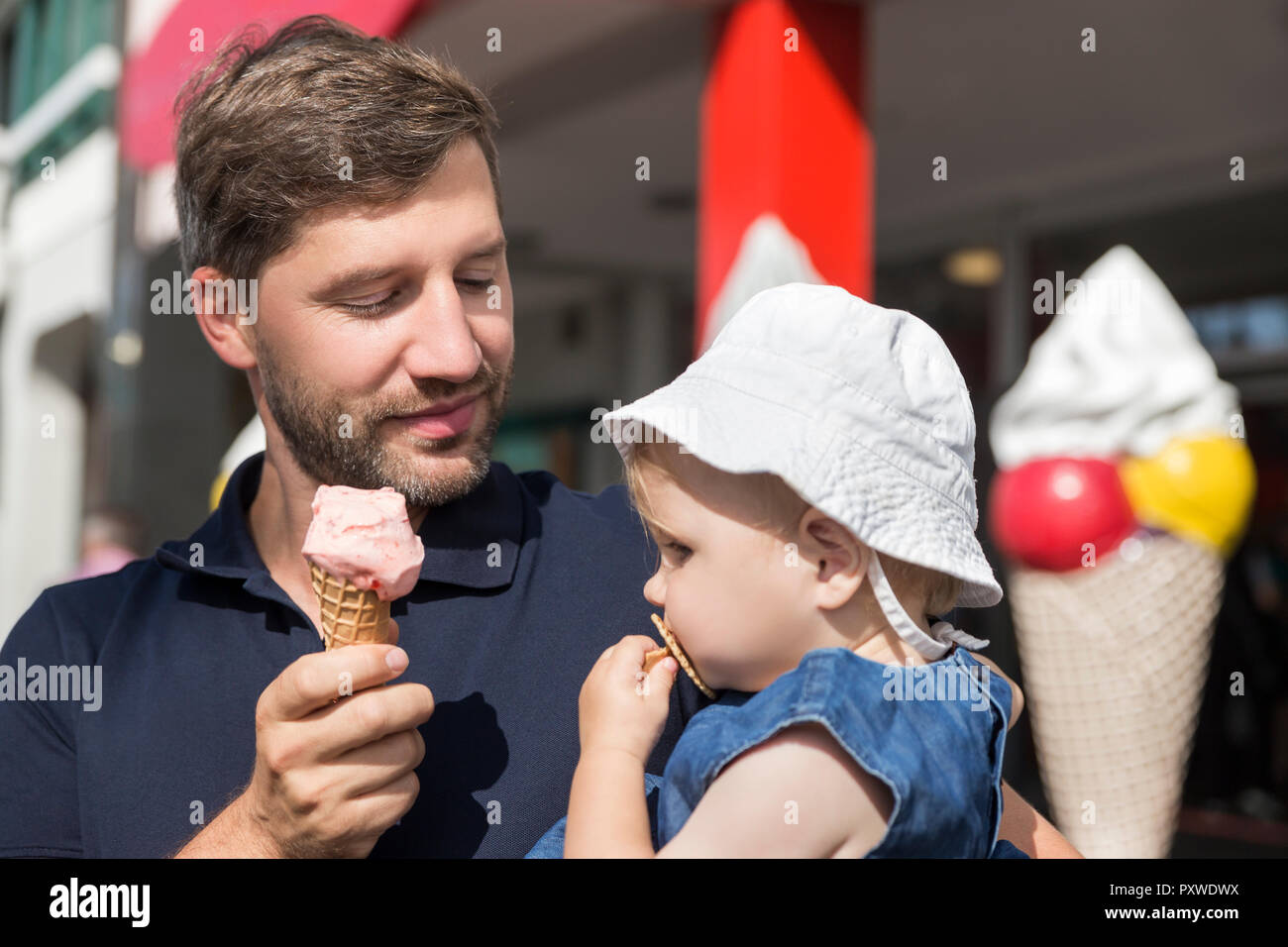 Padre a mangiare il gelato azienda figlia Foto Stock