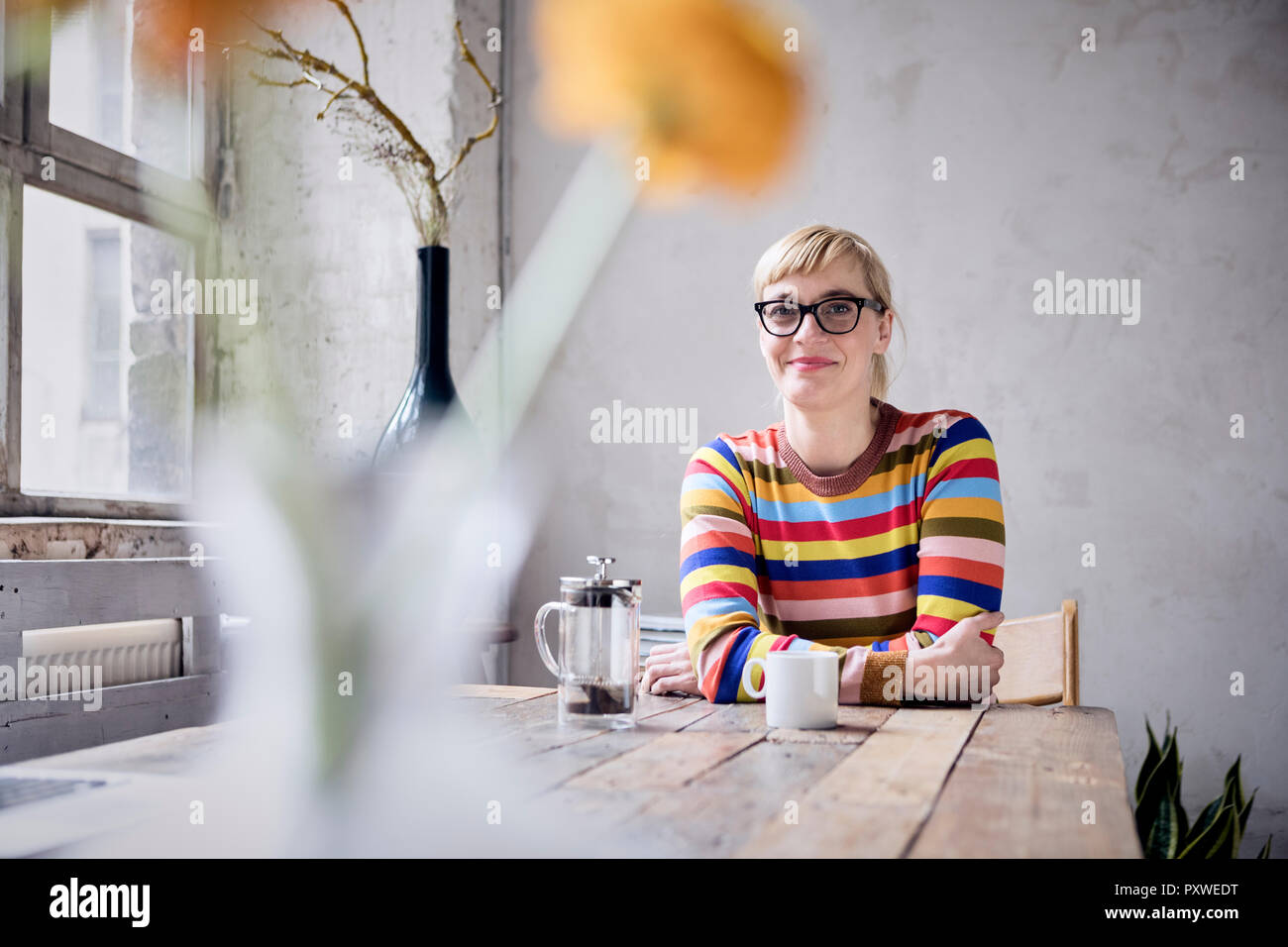 Ritratto di donna sorridente con la tazza di caffè in un loft Foto Stock