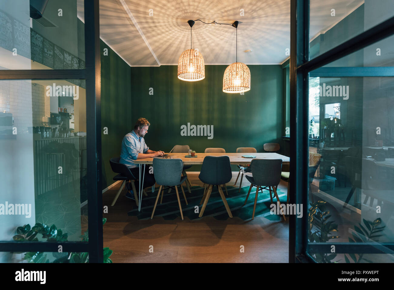 Uomo seduto in ufficio, lavora fino a tardi nella sua azienda start-up Foto Stock