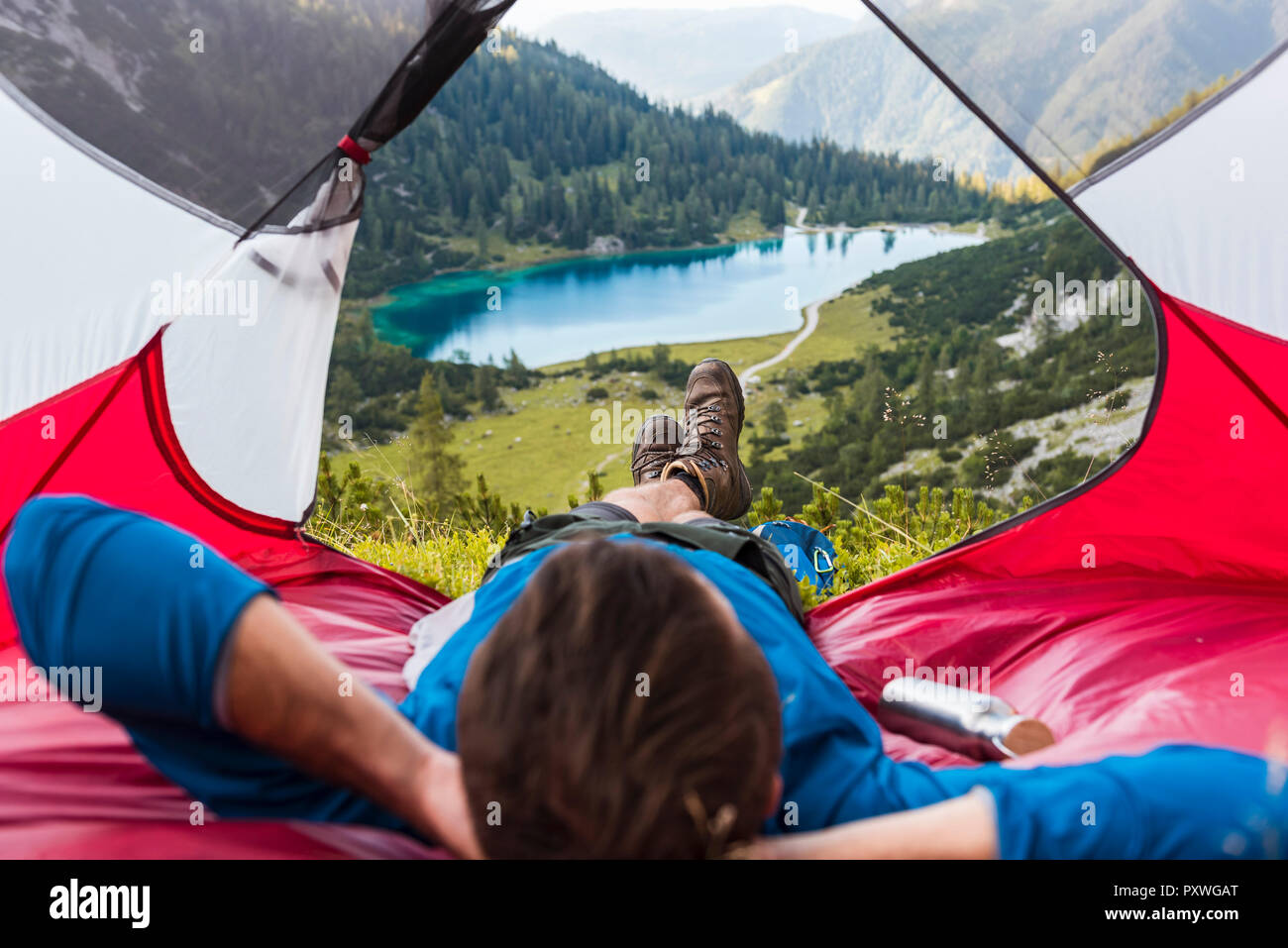 Austria, Tirolo, Escursionista rilassante nella sua tenda in montagna al lago Seebensee Foto Stock