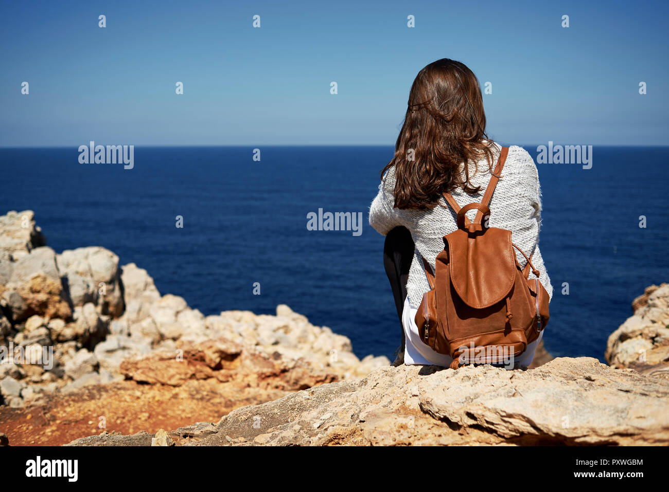 Bruna giovane donna seduta sulla costa, guardando a vista Foto Stock