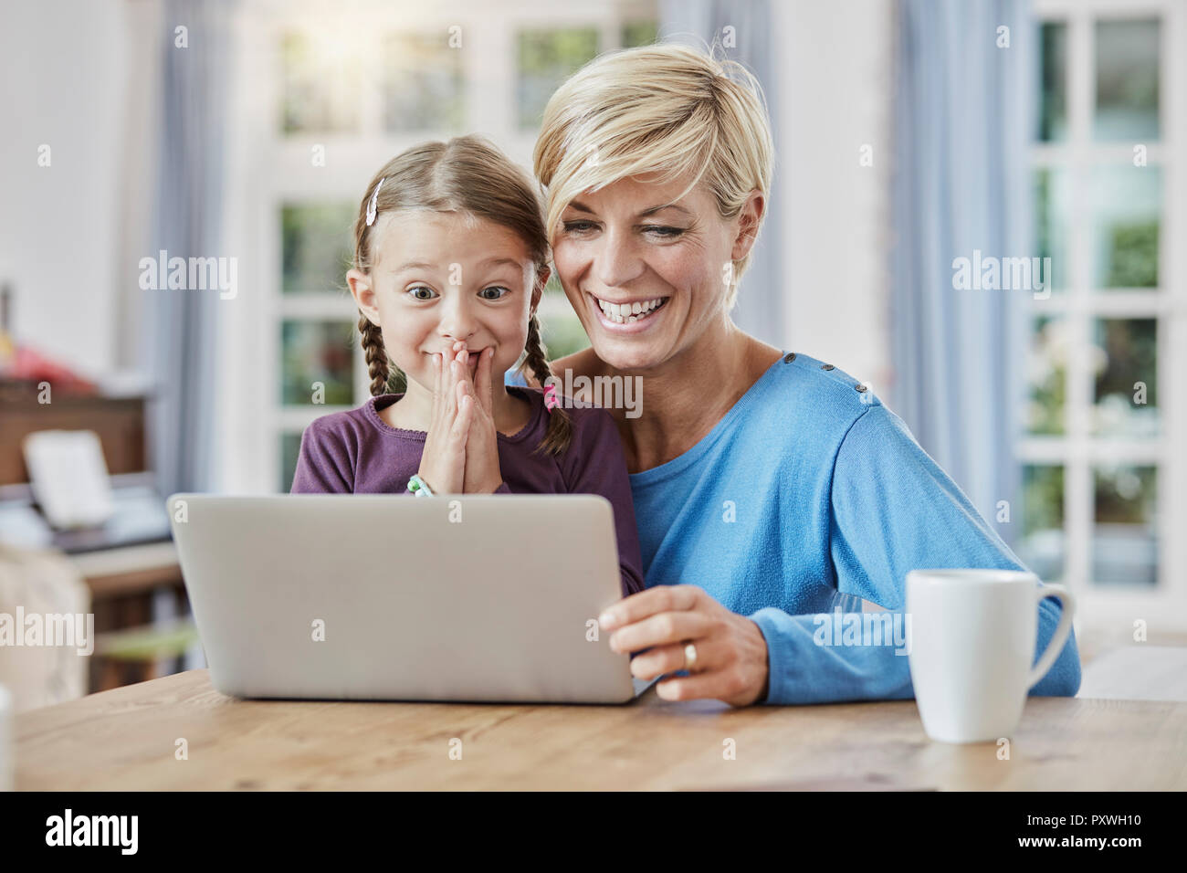 Madre e figlia sorpreso utilizzando portatile a casa Foto Stock
