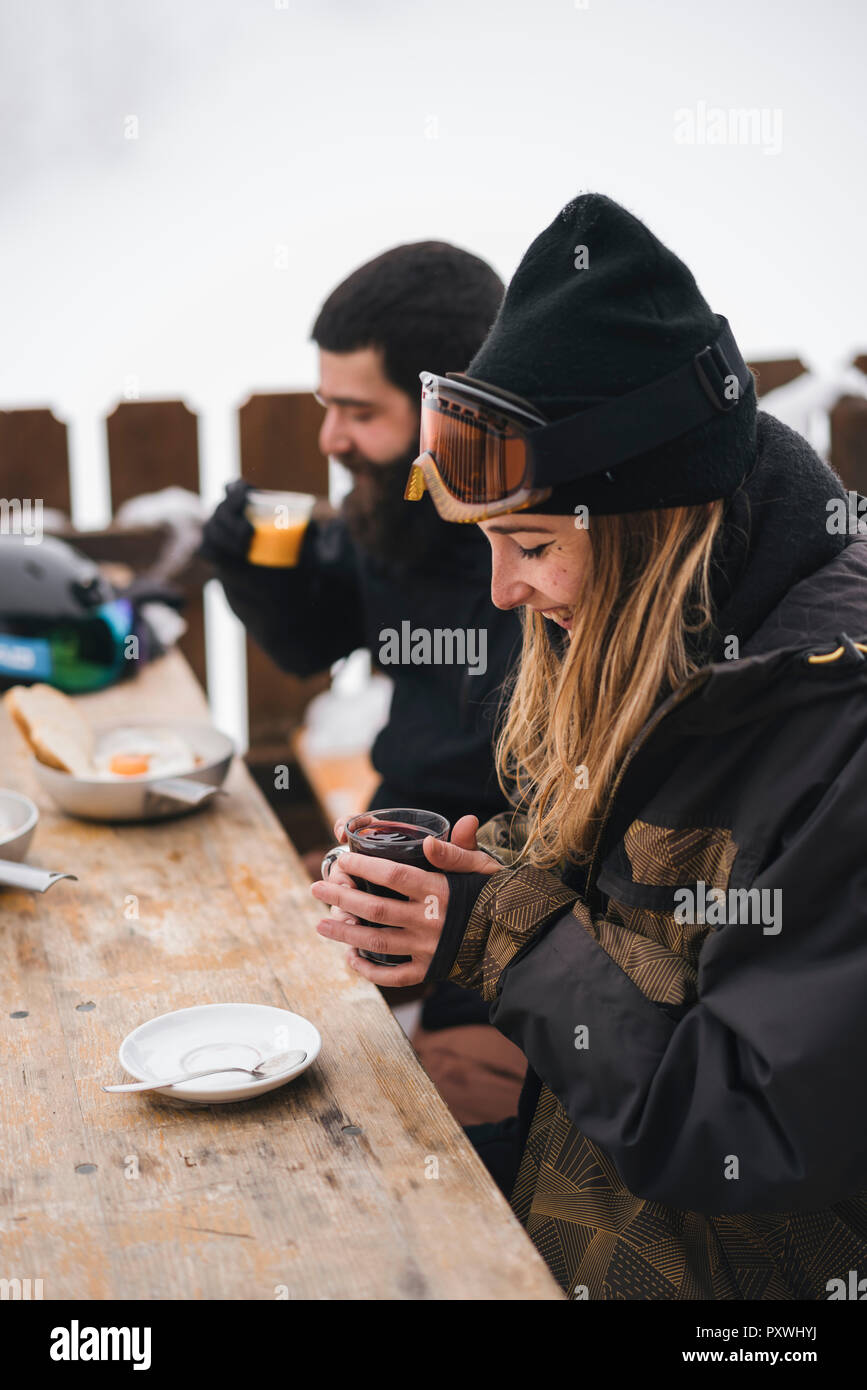 Matura in skiwear avente una bevanda calda al Mountain Lodge Foto Stock