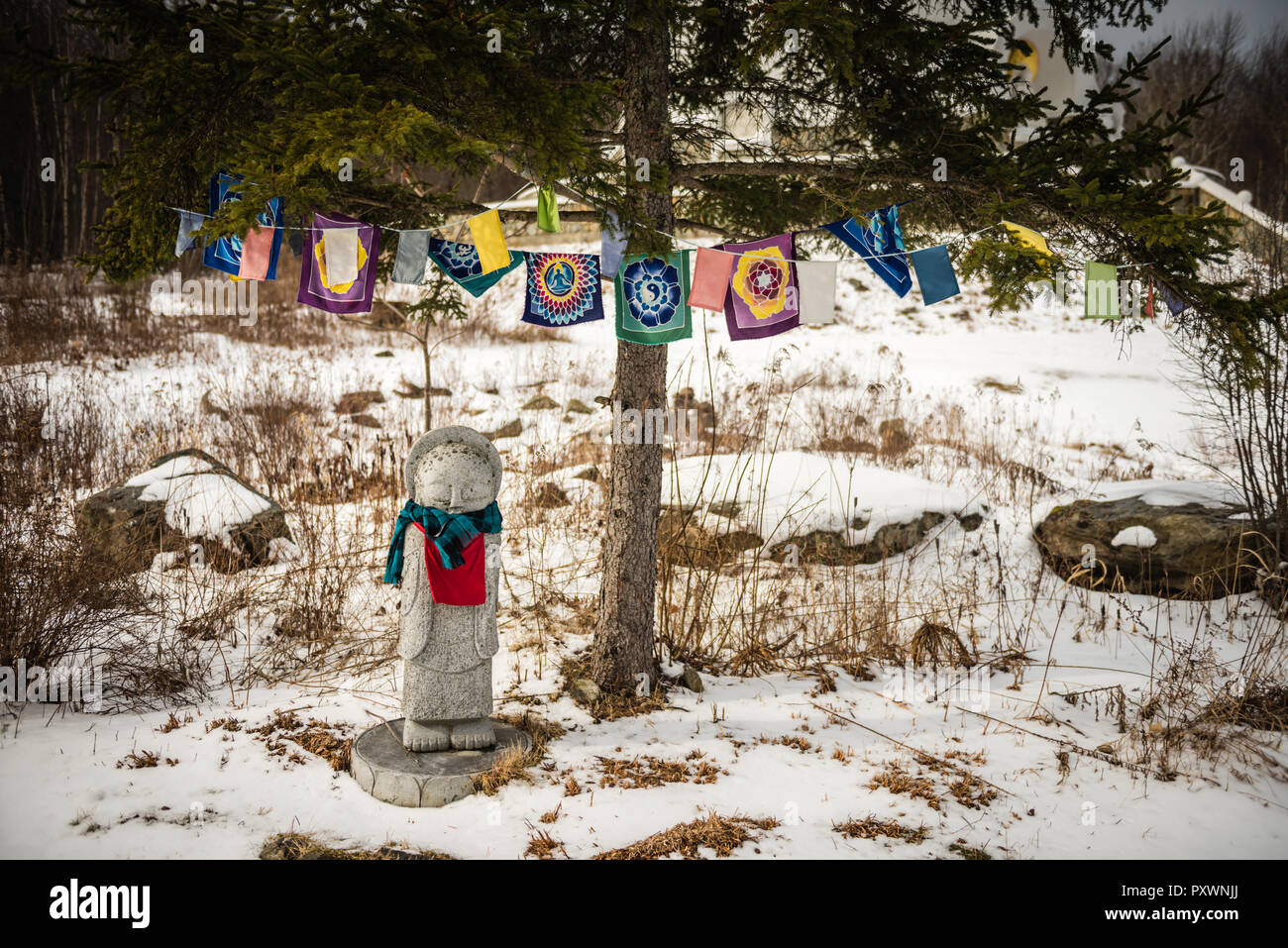 Statua di marmo colorato e bandiere di preghiera su strade coperte di neve la terra del Grafton Pagoda della Pace in Augustine, New York. Foto Stock