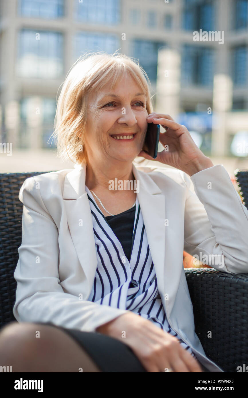Senior imprenditrice è seduta in cafe e parlando al telefono. Foto Stock