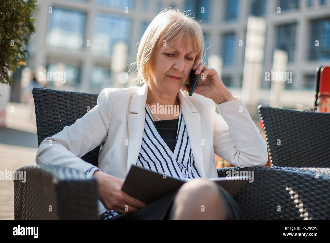 Senior imprenditrice è seduta in cafe e la chiamata per un lavoro. Foto Stock