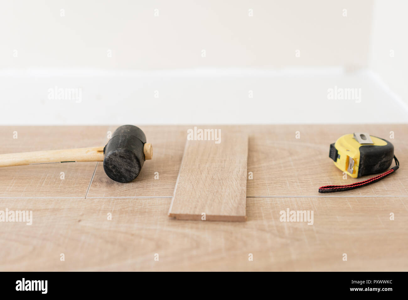 Installazione parquet laminato in interni. Sul pavimento si trovano diversi strumenti di falegname. Il martello e il nastro di misurazione. concetto di riparazione in casa. Foto Stock