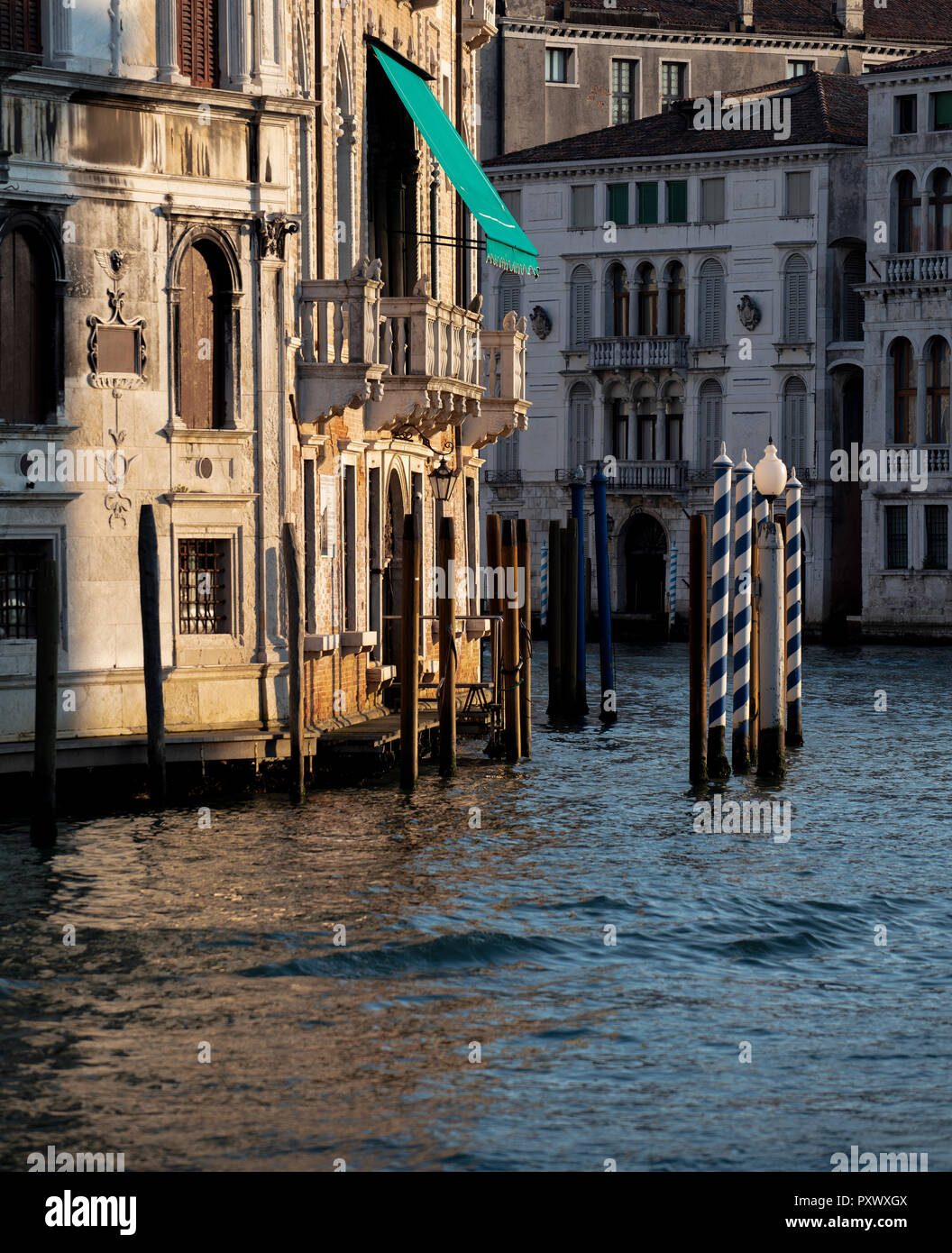 Striping posti di ormeggio al di fuori di un palazzo lungo il Canal Grande a Venezia nella luce della sera. Foto Stock