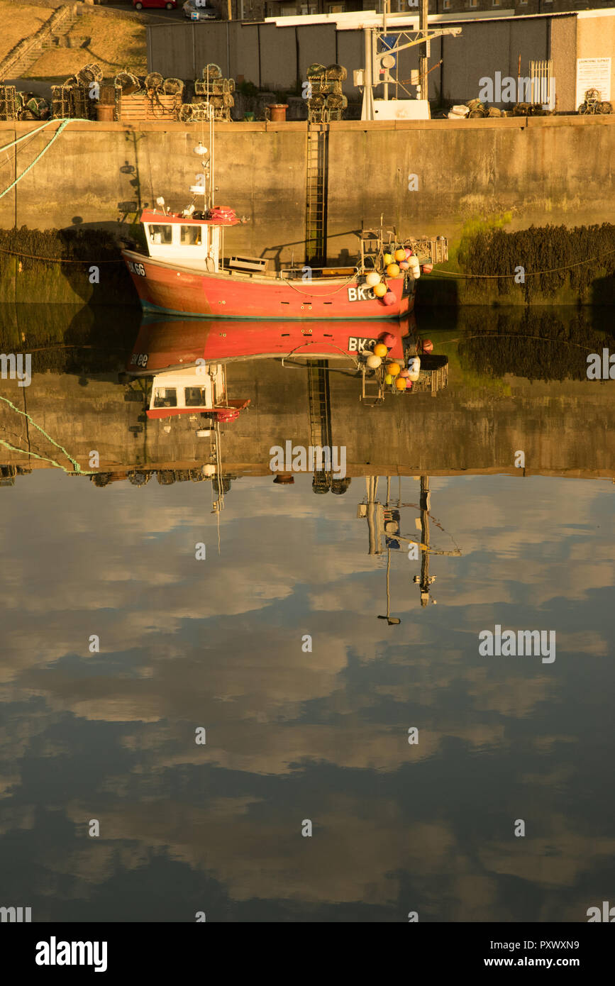 La riflessione di una barca da pesca nel porto di Seahouses, Northumberland, Inghilterra Foto Stock