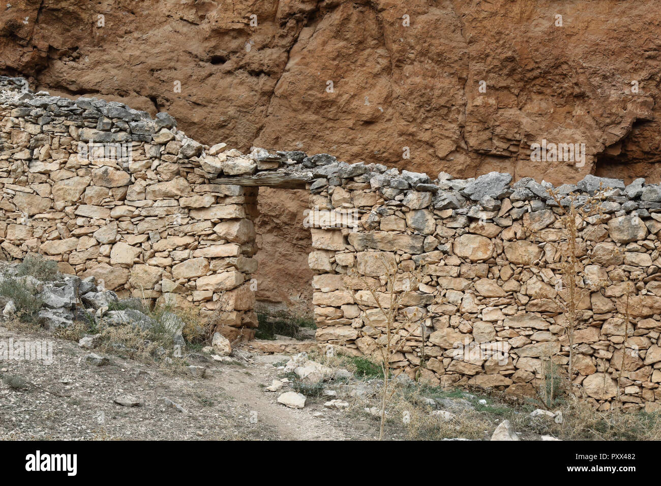 Un rifugio di pastori e bestiame in pietra del muro a secco all'interno di una grotta nella Red Rock ferroso del Barranco de la Hoz Seca canyon, Jaraba, Spagna Foto Stock