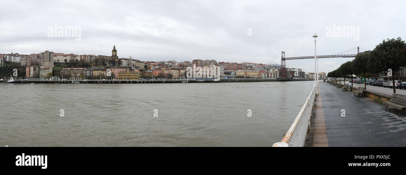 Una vista di Portugalete dalla passeggiata sul fiume, con l'antenna il Ponte di Vizcaya (Puente de Vizcaya) sul fiume Nervion in un nuvoloso giorno di inverno, Spagna Foto Stock